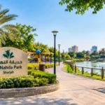 Al Nahda Park Sharjah with landscaped gardens, walking paths, playground and lakeside fountain.